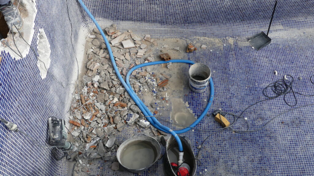 Retirada de zonas deterioradas de gresite durante la preparación de una piscina antes de instalar liner